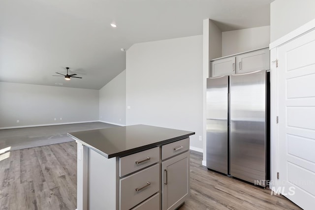 kitchen featuring ceiling fan, light hardwood / wood-style floors, stainless steel fridge, a center island, and vaulted ceiling