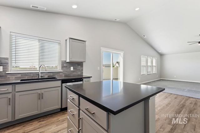 kitchen with gray cabinetry, lofted ceiling, a healthy amount of sunlight, and sink