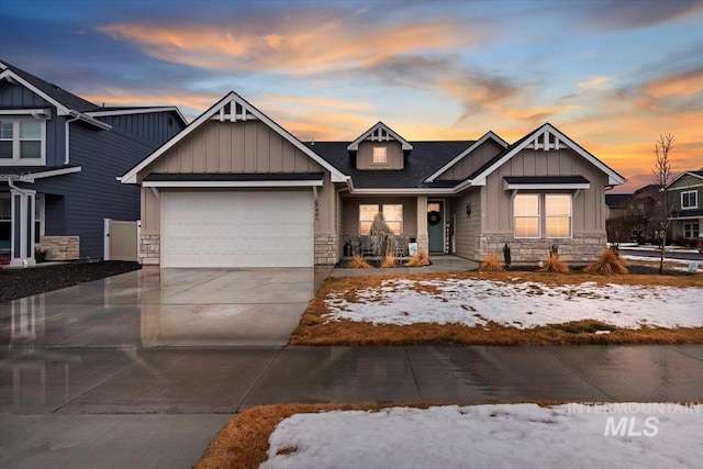 craftsman inspired home featuring roof with shingles, driveway, a garage, stone siding, and board and batten siding