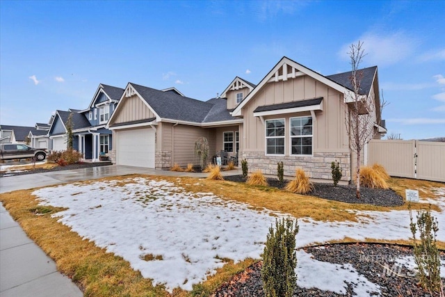 craftsman-style house with fence, stone siding, board and batten siding, driveway, and a garage