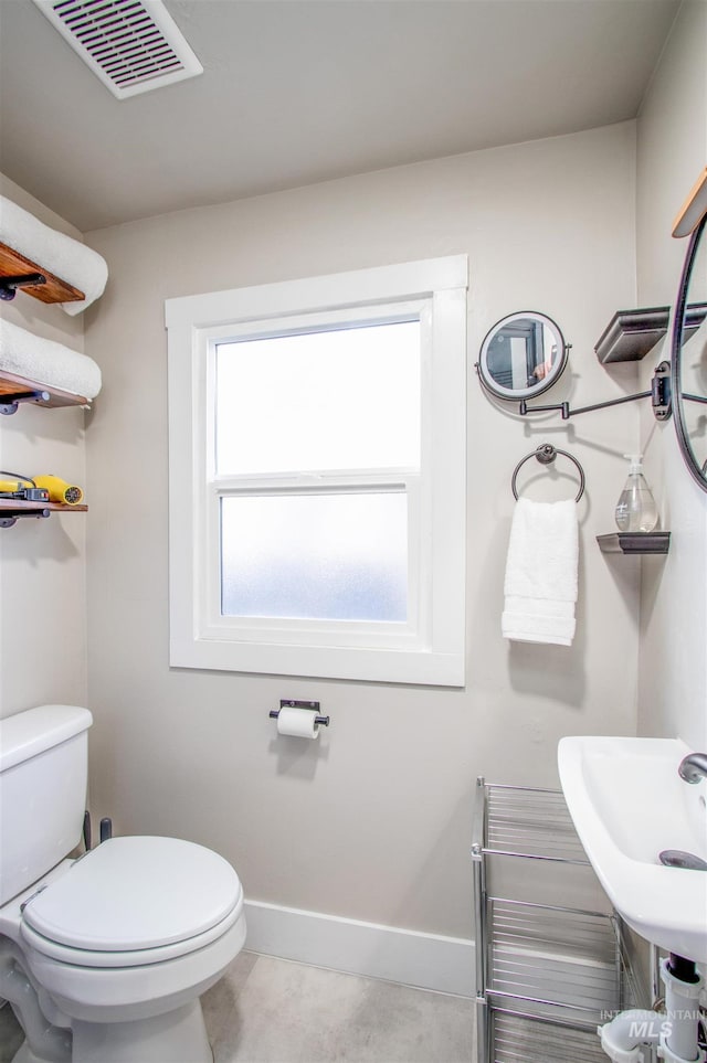 half bath featuring toilet, visible vents, and baseboards