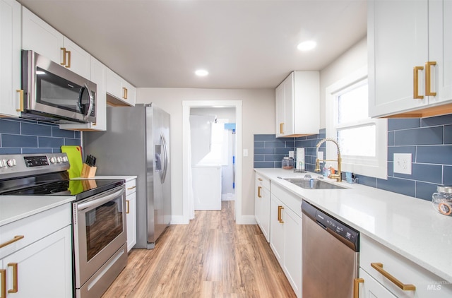 kitchen with light countertops, appliances with stainless steel finishes, a sink, and white cabinets