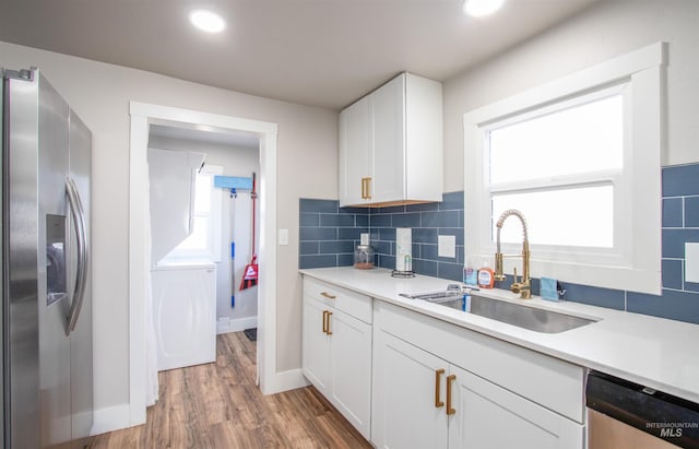 kitchen with a wealth of natural light, washer / clothes dryer, a sink, stainless steel appliances, and backsplash