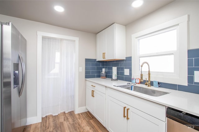 kitchen featuring tasteful backsplash, stainless steel appliances, a sink, and light countertops