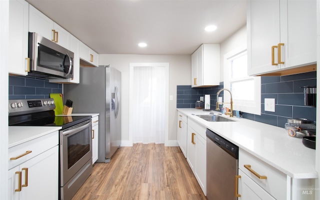 kitchen with stainless steel appliances, a sink, light countertops, and white cabinets