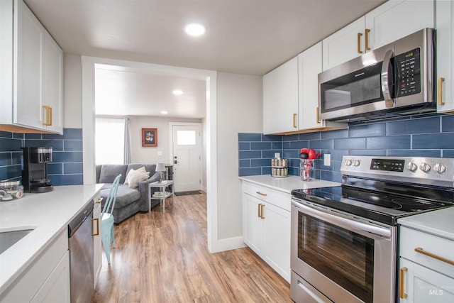 kitchen with white cabinetry, light wood-style floors, open floor plan, light countertops, and appliances with stainless steel finishes