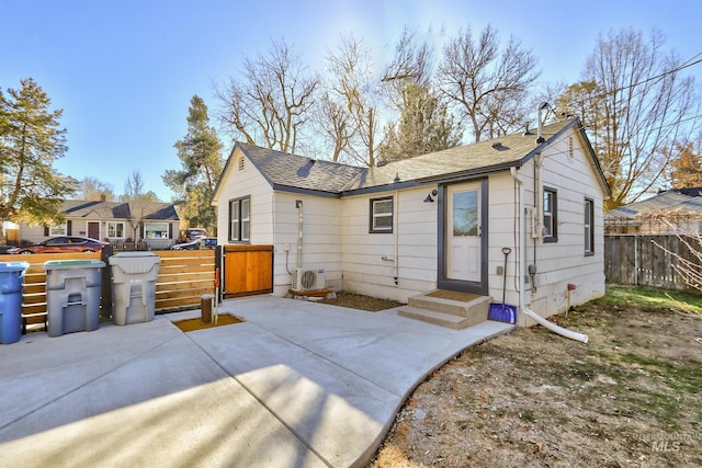 back of house featuring roof with shingles, a patio area, fence, and a gate