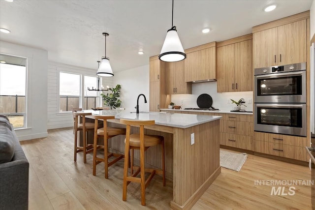 4628 N Camp Creek Ave, Meridian, ID 83646 - kitchen with a sink, white gas stovetop, stainless steel double oven, a kitchen bar, and a center island with sink