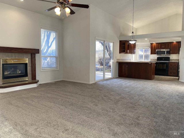 unfurnished living room with baseboards, a tiled fireplace, high vaulted ceiling, and carpet flooring