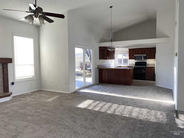 kitchen featuring light carpet, range, stainless steel microwave, open floor plan, and a peninsula