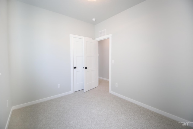 unfurnished room with light carpet, visible vents, and baseboards