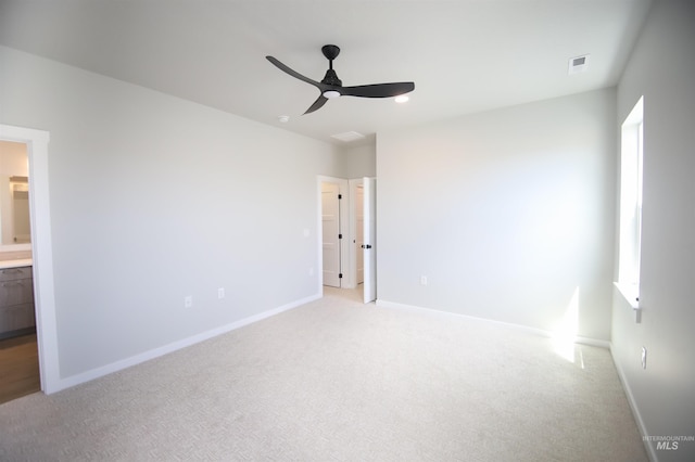 unfurnished bedroom featuring visible vents, ensuite bathroom, a ceiling fan, light carpet, and baseboards