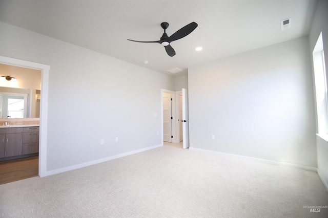 unfurnished bedroom featuring light colored carpet, connected bathroom, visible vents, and baseboards