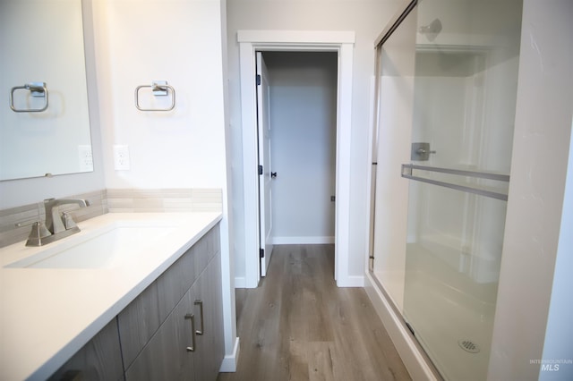 full bathroom with baseboards, wood finished floors, vanity, and a shower stall