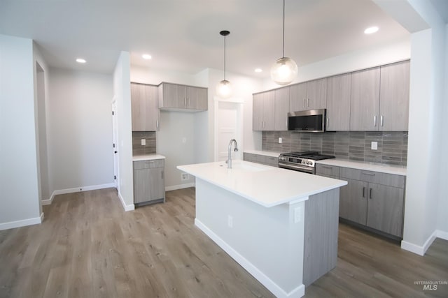 kitchen with appliances with stainless steel finishes, decorative light fixtures, light countertops, gray cabinetry, and a sink