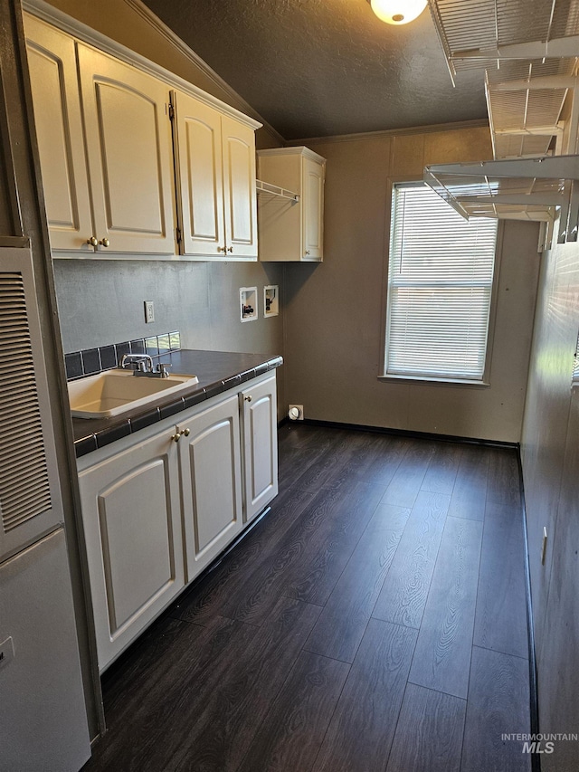 kitchen featuring sink, dark hardwood / wood-style flooring, tile countertops, lofted ceiling, and white cabinets