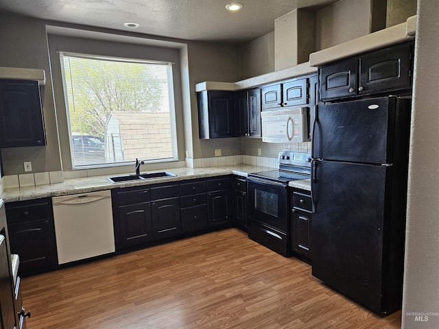kitchen with black appliances, light hardwood / wood-style floors, sink, and a textured ceiling