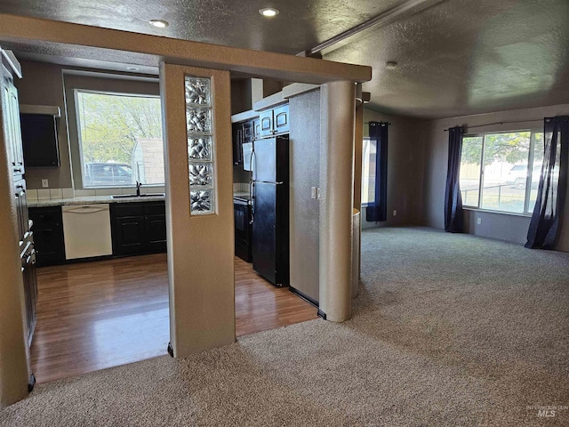 kitchen featuring white dishwasher, black refrigerator, a textured ceiling, and hardwood / wood-style flooring