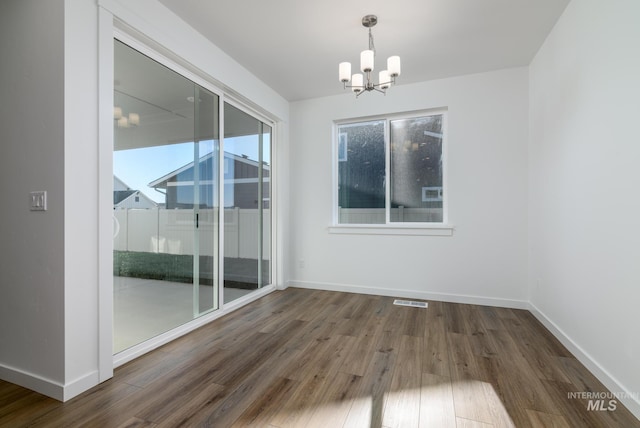 empty room featuring dark hardwood / wood-style flooring and a chandelier