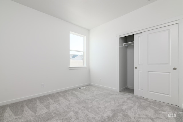 unfurnished bedroom featuring light colored carpet and a closet