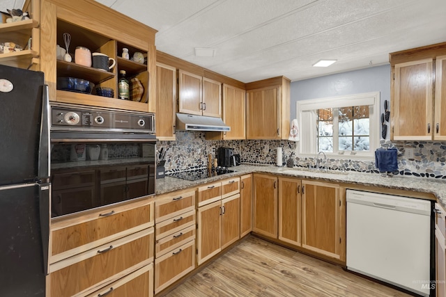 kitchen with light stone countertops, sink, tasteful backsplash, light hardwood / wood-style flooring, and black appliances