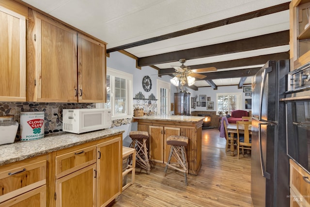 kitchen featuring ceiling fan, light stone countertops, beamed ceiling, light hardwood / wood-style floors, and decorative backsplash