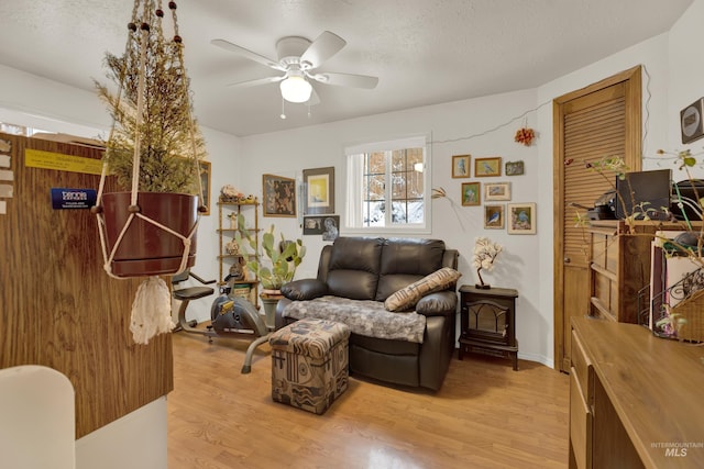 living room with a textured ceiling, light hardwood / wood-style floors, and ceiling fan