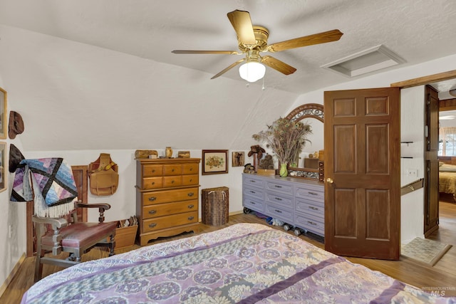 bedroom with a textured ceiling, ceiling fan, light hardwood / wood-style floors, and vaulted ceiling