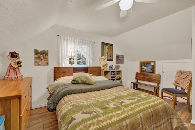 bedroom featuring hardwood / wood-style floors, a textured ceiling, ceiling fan, and lofted ceiling