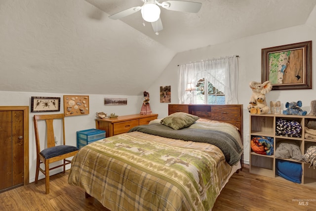 bedroom with ceiling fan, wood-type flooring, a textured ceiling, and vaulted ceiling