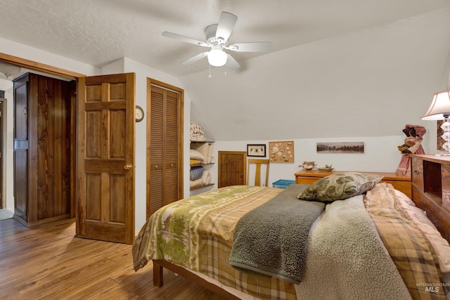 bedroom with ceiling fan, a closet, wood-type flooring, and lofted ceiling