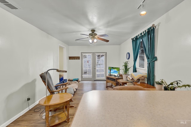 sitting room featuring french doors, ceiling fan, and dark wood-type flooring