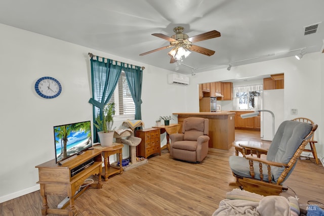 living room featuring a wall mounted air conditioner, light wood-type flooring, rail lighting, a wealth of natural light, and ceiling fan