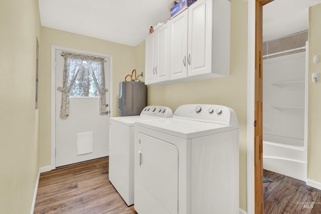 laundry area featuring light hardwood / wood-style floors, independent washer and dryer, cabinets, and electric water heater