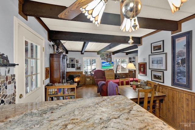 dining room with vaulted ceiling with beams, wood walls, and ceiling fan