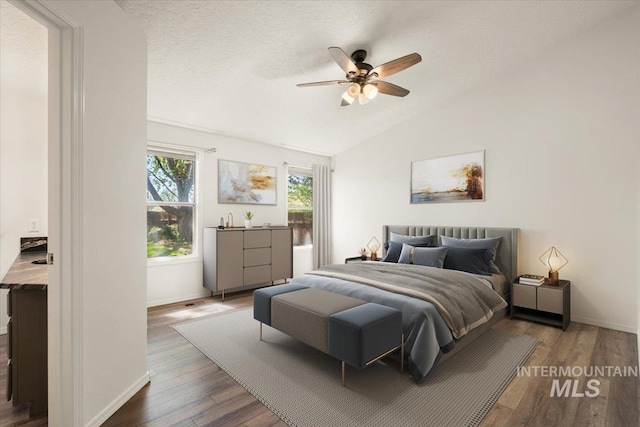 bedroom featuring baseboards, a ceiling fan, wood finished floors, and vaulted ceiling