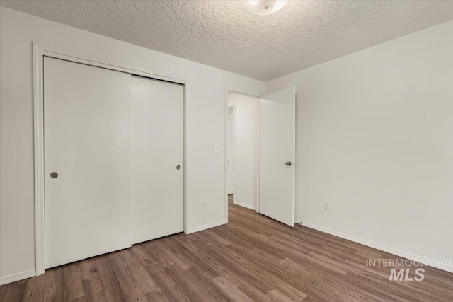 unfurnished bedroom with a closet, baseboards, and wood finished floors