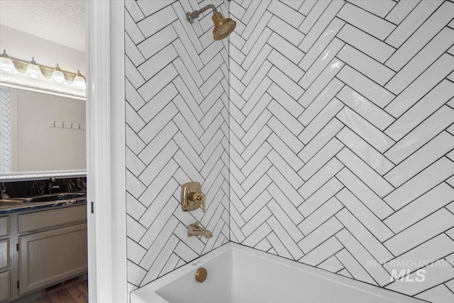 bathroom featuring vanity, shower / bathing tub combination, and a textured ceiling