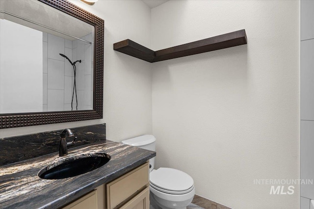 bathroom featuring vanity, a shower, and toilet