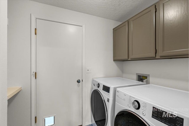 laundry area with a textured ceiling, cabinet space, and washing machine and dryer