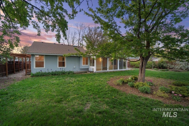 rear view of property featuring fence, a yard, and a sunroom