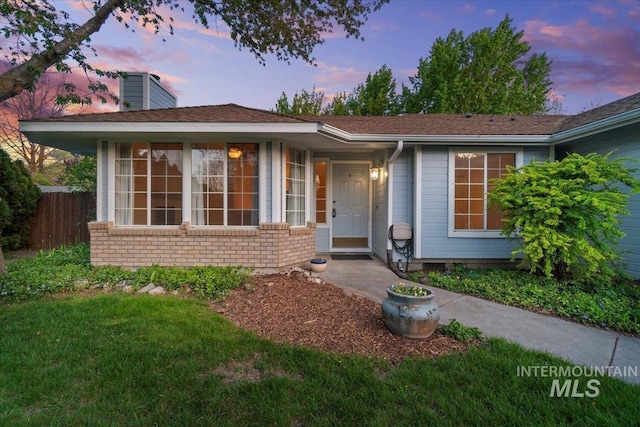 ranch-style home with brick siding, fence, a yard, and a chimney