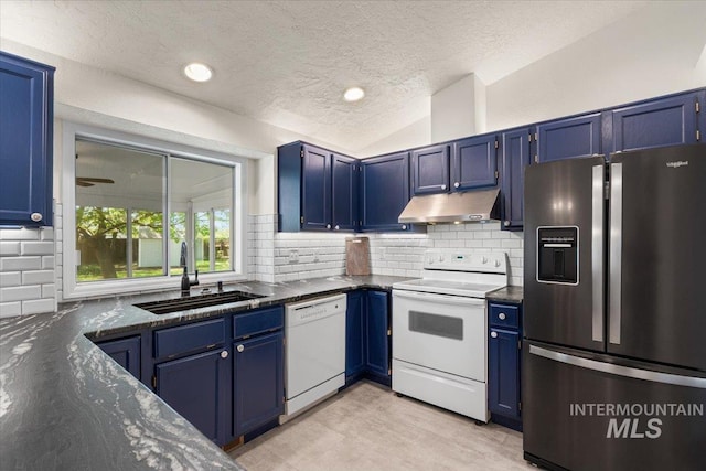 kitchen with white appliances, under cabinet range hood, a sink, and blue cabinets