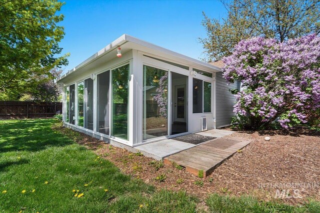 view of side of home with a yard, fence, and a sunroom