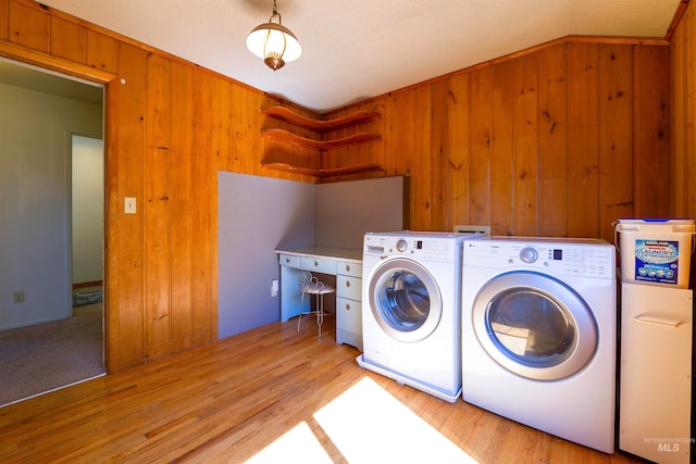 clothes washing area featuring laundry area, wooden walls, separate washer and dryer, and light wood-type flooring