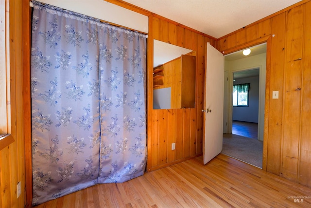spare room with wooden walls, ornamental molding, and wood finished floors