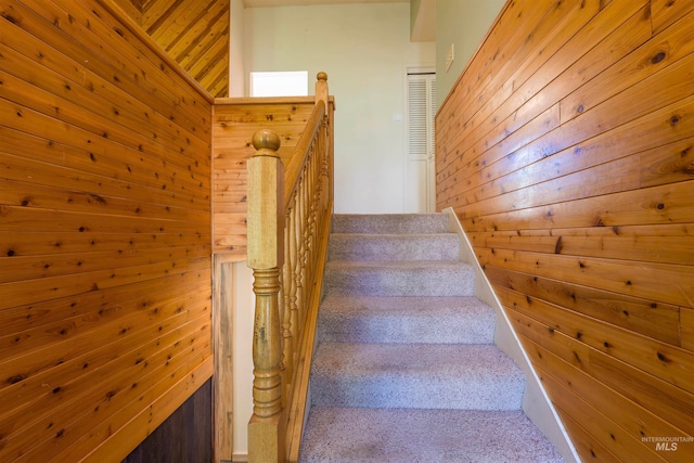stairway featuring wood walls