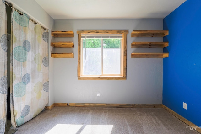 unfurnished room with carpet and baseboards