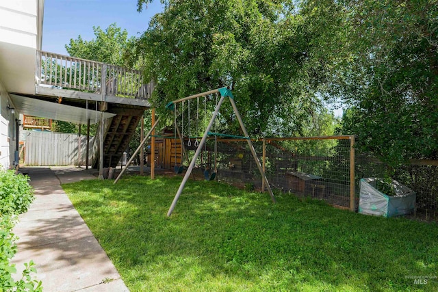 view of playground featuring stairway, a lawn, a vegetable garden, and fence