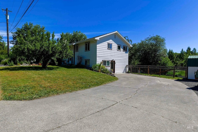 view of side of home with concrete driveway, a lawn, and fence